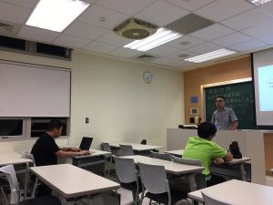 Two students in a classroom with the instructor at the front