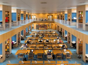 Inside of a library with tables and people studying at the tables