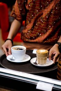 Person holding a tray with two coffees.