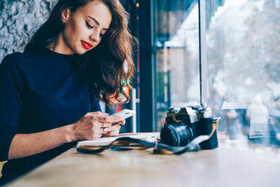 Woman sitting at a table sending a text message on a mobile phone